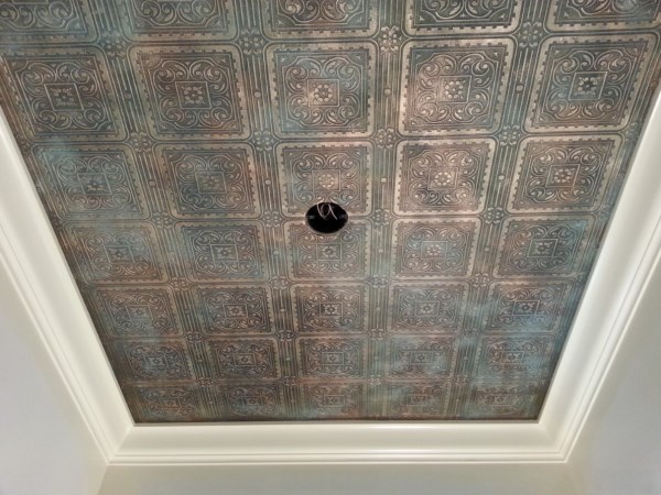 Paintable wallpaper finished in bronze and gold with a bluegreen patina in powder room ceiling 